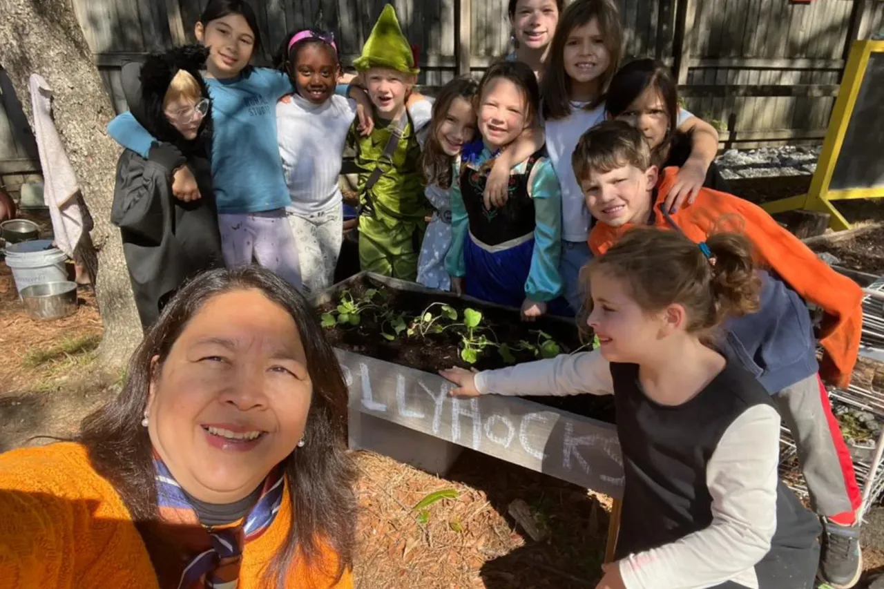 Children and educator smiling in the school garden area